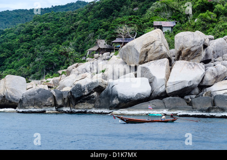 Ein Longtail-Boot mit einer thailändischen Flagge geht von spektakulären großen Felsbrocken auf Koh Tao im Golf von Thailand Stockfoto