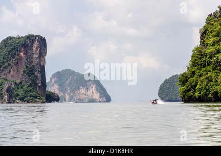 Longtail-Boot spritzt Wildwasser durch spektakuläre Klippe Kalksteininseln in Ao Phang-Nga Marine National Park in Süd-Thailand Stockfoto