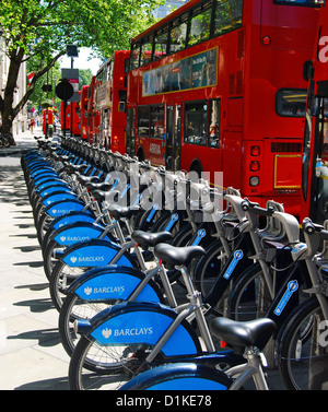 Rote Busse gebündelt in einem Konvoi vorbei an einer Reihe von Boris Bikes zu mieten in der Nähe von Trafalgar Square an einem Sommertag in London UK. Stockfoto