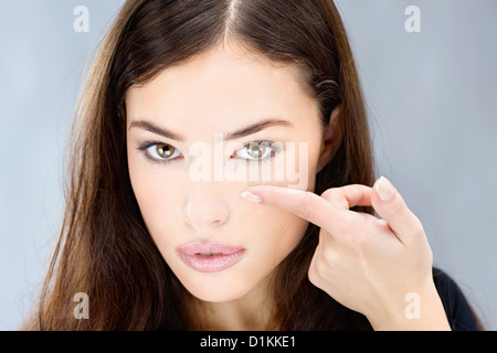 Junge Frau, die Finger vor ihrem Auge Kontaktlinse festhalten Stockfoto