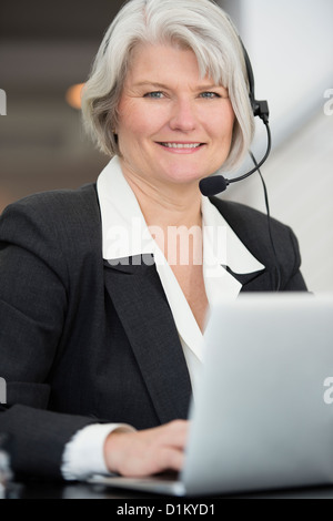 Lächelnd Geschäftsfrau in Kopfhörer am Laptop tippen Stockfoto