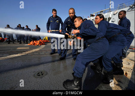 Matrosen behandeln einen Feuerwehrschlauch während Schadensbegrenzung Olympics an Bord der geführte Flugkörper-Zerstörer USS Jason Dunham (DDG-109). Jason Dunham ist in den USA bereitgestellt 5. Flotte Aufgabengebiet Durchführung von maritimer Sicherheitsoperationen, Theater Sicherheitsbemühungen Zusammenarbeit und Unterstützung Missionen für die Operation Enduring Freedom... Arabisches Meer (Dec.29, 2012) U.S. Navy Photo Stockfoto