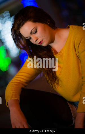 Eine 18 19 20 jährige Frau Mädchen allein in der Nacht alleine, unscharf gestellt Lichter im Hintergrund Stockfoto