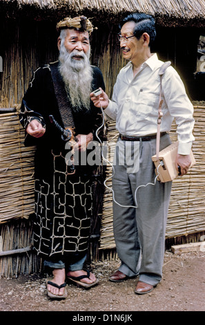 Der japanische Sprachwissenschaftler Prof. Kyosuke Kindaichi-Band zeichnet die uralten Geschichten eines bärtigen Ainu-Dorfchefs 1962 auf der Insel Hokkaido in Japan auf. Stockfoto