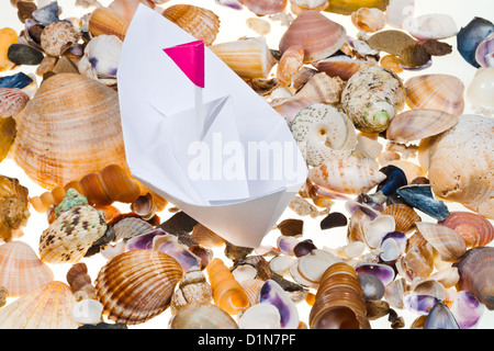 weißes Papierboot auf Grund von Muscheln Stockfoto