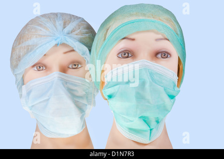 zwei Dummy-Arzt Frauenköpfe tragen Textile OP-Cap und medizinische Schutzmaske auf blauem Hintergrund isoliert Stockfoto
