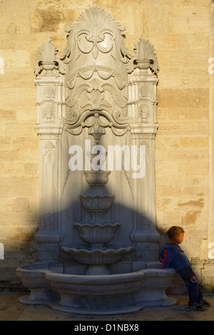 Kleiner Junge am Steinbrunnen mit Schatten der Kuppel bei Eyüp Sultan Moschee Istanbul-Türkei Stockfoto