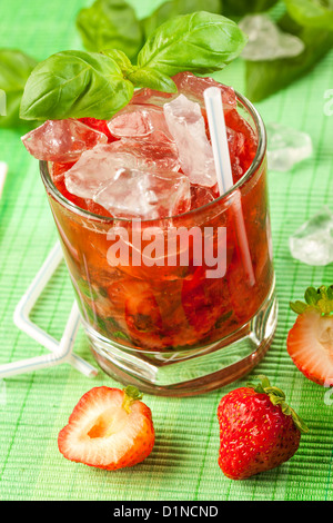 Rotes Getränk auf einem grünen Hintergrund und Eis Stockfoto
