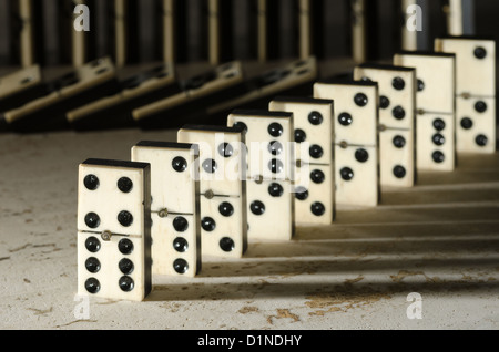 Reihen von aufgereiht altes Elfenbein und Ebenholz Bronze angehefteten stehende Domino blockiert Stücke auf weißem Tan Travertin-Marmor Stockfoto