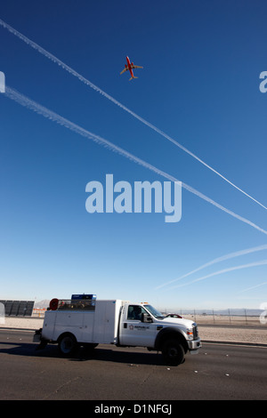 Flugzeug, Aufbruch in blauer Himmel mit Kondensstreifen am Ende der Start-und Landebahn über vorbei an LKW am Mccarran internationaler Flughafen Stockfoto