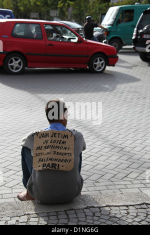 Mann sitzt auf dem Bürgersteig in Tirana mit einem Pappschild Stockfoto