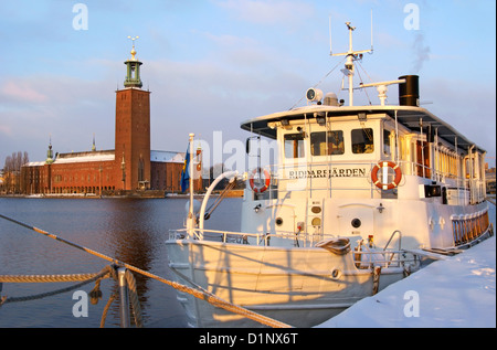 Stockholm, Schweden. Riddarfjärden Boot verankert auf Riddarholmen Uferpromenade. Rathaus im Hintergrund während einem Wintermorgen. Stockfoto