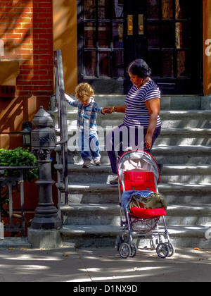 Ein afrikanisch-amerikanischer Kindermädchen führt ein Kind auf der Treppe ein Reihenhaus aus rotem Backstein auf der State Street in Brooklyn Heights, New York. Stockfoto