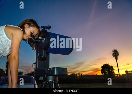 In der Abenddämmerung sieht eine acht-jährige Mädchen durch das Okular eines katadioptrischen astronomischen Teleskops in ihrem Hinterhof California. Stockfoto