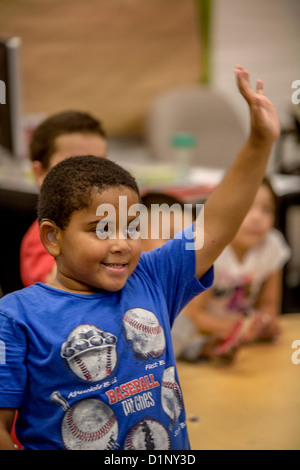 Eine begeisterte Hörgeschädigte afroamerikanische Grundschule junge hält seine Hand in der Klasse in Riverside, Kalifornien. Stockfoto