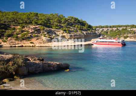 Magaluf, Mallorca, Balearen, Spanien. Blick über das türkisfarbene Wasser des Cala Portals Vells, bunte Boot vor Anker. Stockfoto