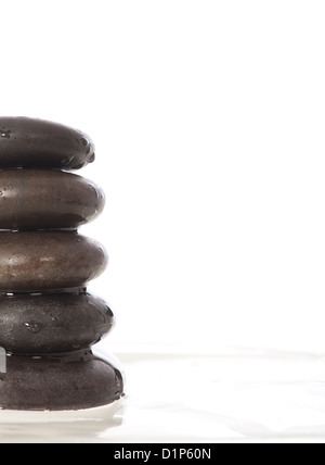 Grüne Blätter über Zen Stones Pyramid auf Wasseroberfläche Stockfoto