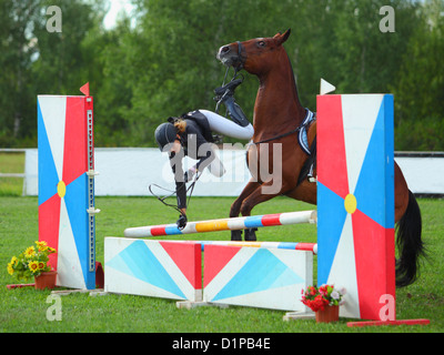 Fahrer in das Hindernis während der Teilnahme an der Show Jumping-Veranstaltung von ihrem Pferd fallen Stockfoto