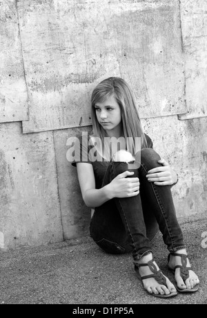 Traurige Teenager-Mädchen sitzen auf dem Boden in der Gasse. Stockfoto