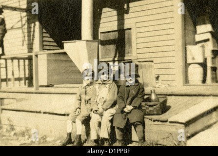 Ca. 1920 Foto, drei Kinder sitzen auf der Veranda mit Milchflasche, wahrscheinlich New England, USA. Stockfoto