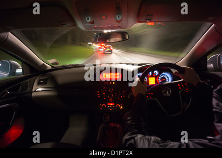 Fahrer-Perspektive fahren Sie schnell in Richtung zwei Autos in der Nacht auf der Landstraße. Stockfoto