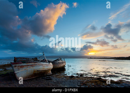 Verlassene Fischerboote bei Sonnenaufgang auf der Isle of Mull in der Inneren Hebriden, Schottland, UK, mit Blick auf das schottische Festland Stockfoto