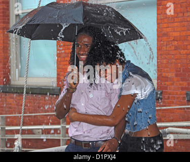 Long Island City, Queens New York City. Zwei schön aussehende Jugendliche unter einem Regenschirm im Regen. Stockfoto