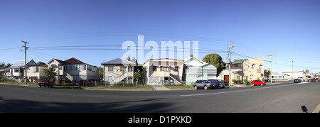 Panoramablick auf eine ruhige Wohnstraße mit Häusern und geparkten Autos unter einem klaren blauen Himmel Stockfoto