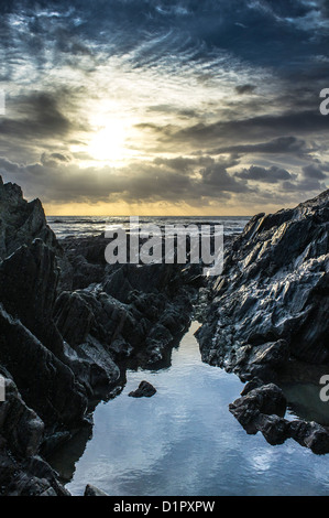 Dramatische Aussicht auf den Sonnenuntergang über dem Meer vom felsigen Strand. Ayrmer Cove, Devon. GROSSBRITANNIEN Stockfoto