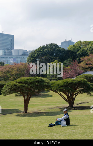Mann sitzt in Shinjuku Gyōen Nationalgarten, Shinjuku Park. Stockfoto