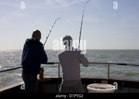 zwei Männer Angeln auf Wolfsbarsch im Ärmelkanal, mit Stangen, abseits die Rückseite eines Bootes. Stockfoto