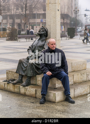 Müde Touristen ruht neben einer bronzenen-Skulptur eines Pilgers mit schmerzenden Füßen in der Plaza de San Marcos - Leon, Spanien, Europa Stockfoto