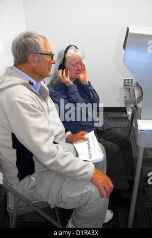 Blinde und Sehbehinderte Frau mit einem Kopfhörer für voting Hilfe in einem Wahllokal in Boise, Idaho, USA. Stockfoto