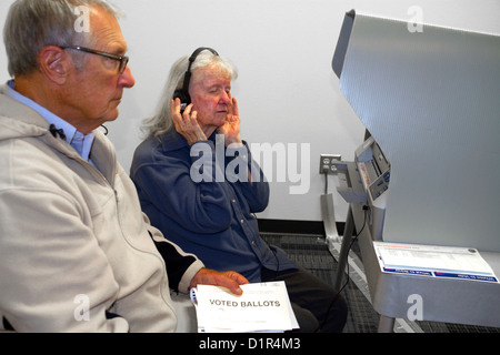 Blinde und Sehbehinderte Frau mit einem Kopfhörer für voting Hilfe in einem Wahllokal in Boise, Idaho, USA. Stockfoto