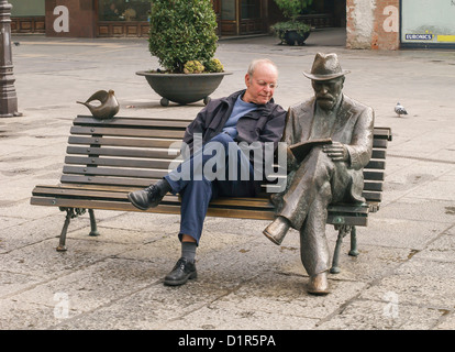 Älterer Mann Standortwahl auf Bank als nächstes um bronze-Skulptur des Mannes lesen - Leon, Spanien, Europa Stockfoto