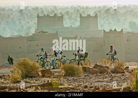 Marokko, in der Nähe von Zagora, Kasbah Ziwane. Sonnenaufgang über Oase und Palmen. Kasbah und Ksar. Kinder zur Schule gehen. Stockfoto