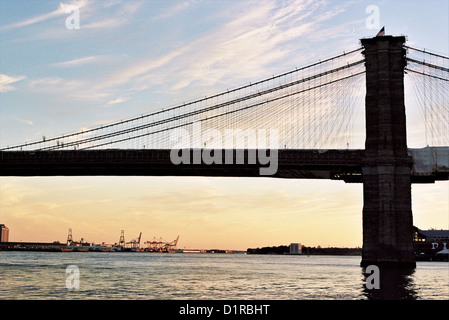 Silhouette von New York Citys Brooklyn Bridge kontrastiert gegen die Rötung Horizont am Abend. Stockfoto