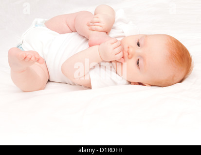 Cute Baby Girl saugen ihre Zehen auf weißem Hintergrund Stockfoto