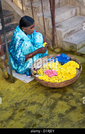 Indische Frau Ringelblumen in einem Korb für hindu Puja Angebote zu verkaufen. Andhra Pradesh, Indien Stockfoto