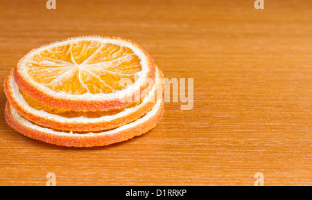 Drei Scheiben getrocknete Orange auf Holztisch Stockfoto