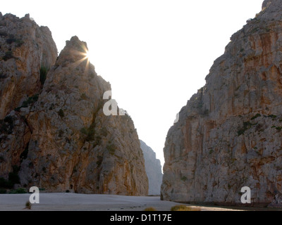 Sa Calobra, Mallorca, Balearen, Spanien. Sonnenstrahlen hinter Klippen an Mündung des Torrent de Pareis Schlucht erscheinen. Stockfoto