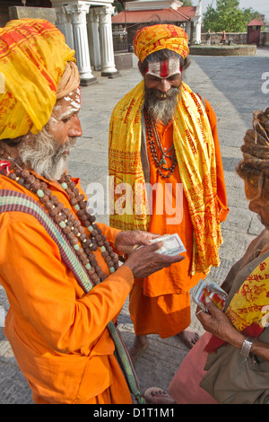 Sadhu heilige Männer Geld an den brennenden Ghats in Pashupatinath Tempel auf den Bagmati Fluss Kathmandu Nepal Asien zählen Stockfoto