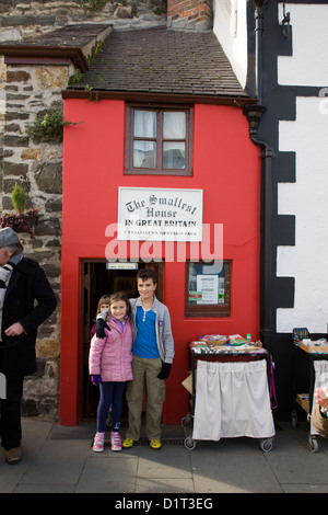 Kinder posieren für ein Foto vor dem kleinsten Haus in Großbritannien, Conwy, Wales Stockfoto