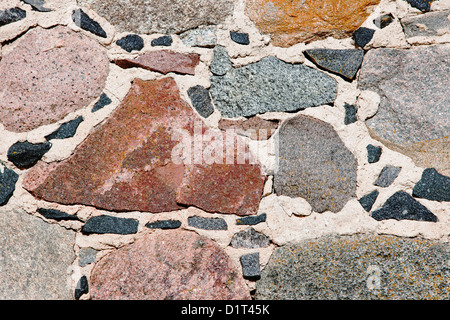 Fragment einer alten handgemachten steinernen Mauer mit bunten Steinen Stockfoto