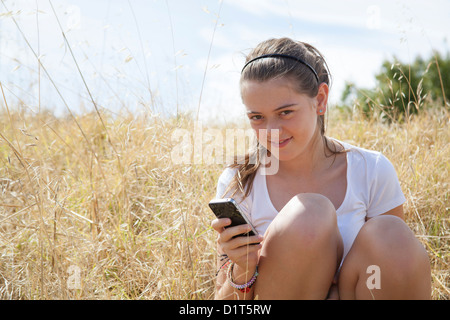 ein junges Mädchen mit ihrem Handy das lange Gras Stockfoto