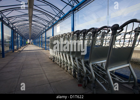 Reihe von Gepäckwagen am London City Airport Stockfoto