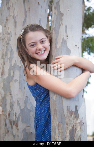 ein junges Mädchen spielt verstecken und suchen im Wald Stockfoto