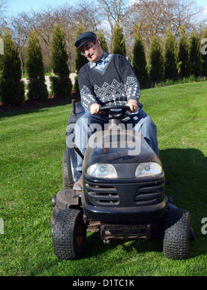 Ältere Mann sitzt auf schwarzen kleinen Gartentraktor und schneiden Rasen im Garten, Vorderansicht Stockfoto
