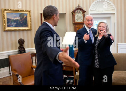 US-Präsident Barack Obama verweist auf den Fotografen als Vize-Präsident Joe Biden und US-Außenministerin Hillary Rodham Clinton reagieren nach dem versehentlich Fallenlassen ihre Informationspapiere auf dem Teppich im Oval Office des weißen Hauses 30. Januar 2012 in Washington, DC. Stockfoto