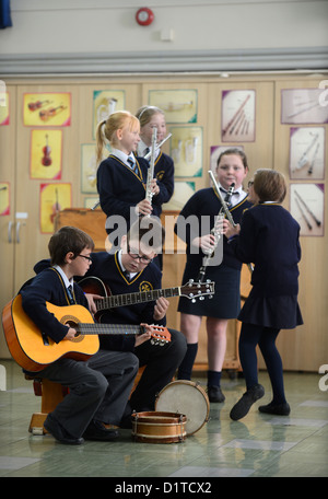 Jungen-Praxis auf ihre Gitarren während eine Musikstunde Muttergottes & St. Werburgh der katholischen Grundschule in Newcastle-under-Lyme, Stockfoto